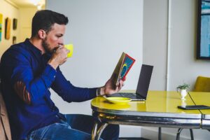 Mężczyzna pije kawę przy laptopie